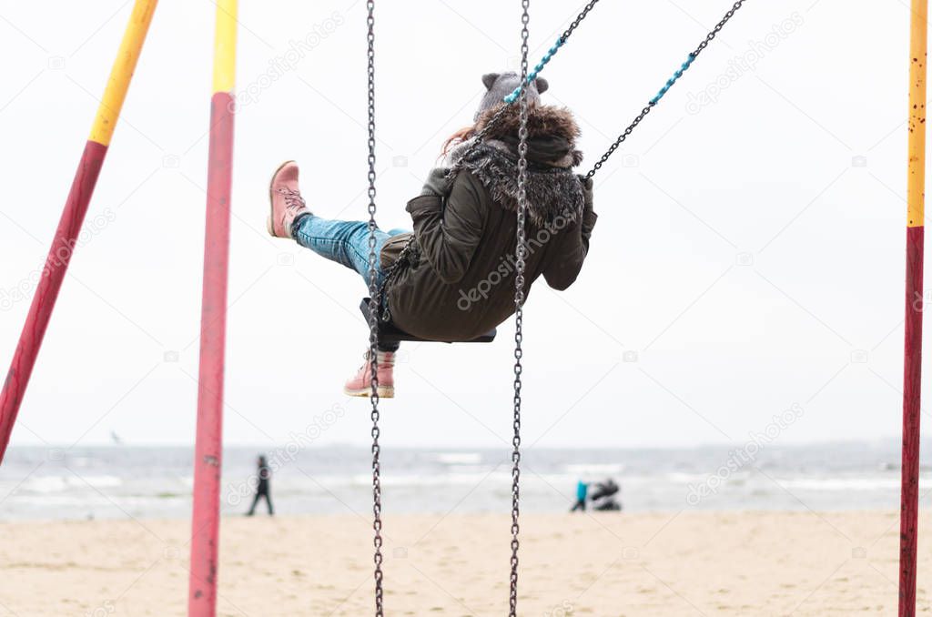 Happy girl swinging at the beach