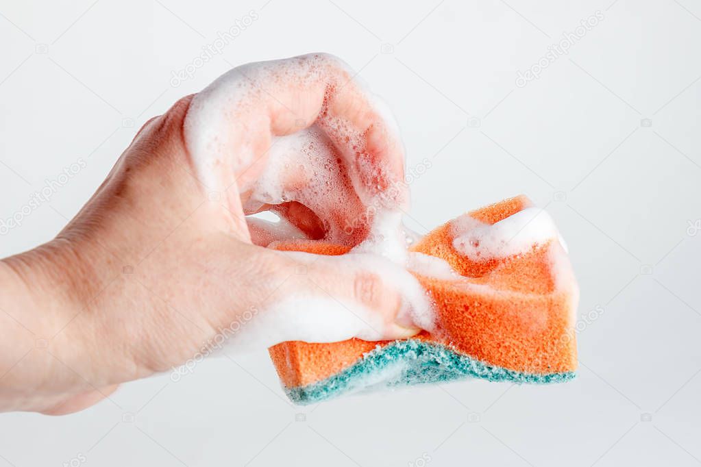 Hand grasps sponge for washing dishes on white background