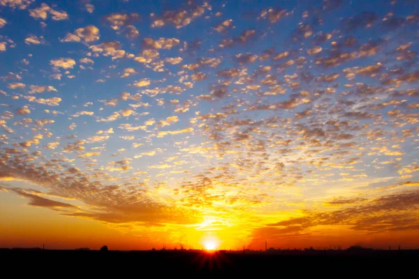 Západ slunce na zamračené obloze nad průmyslovým městem — Stock fotografie