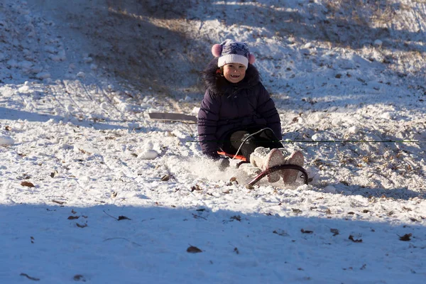 Mutlu ve heyecanlı kız yokuş aşağı kızakla karlı bir günde. Gülüyor ve o yokuş aşağı bir kış günü açık havada üzerinde halletme kar sırasında slaytlar süre heyecan gösterilen sevimli kız