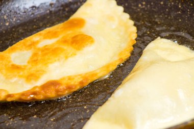 Chebureks pişirme süreci. Beyaz ve Doğu doldurulmuş kuzu ve baharatlı çeşnilikler ile ince mayasız hamur yapılmış bir patty besindir. Cheburek - et ve soğan ile kızarmış pasta.