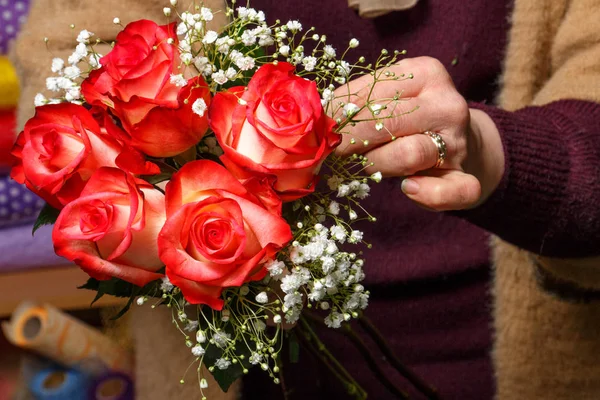 Florist makes a bouquet of red roses