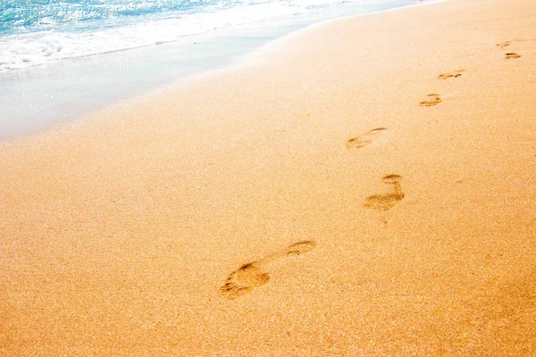 Следы с детских ног в чистом морском песке — стоковое фото