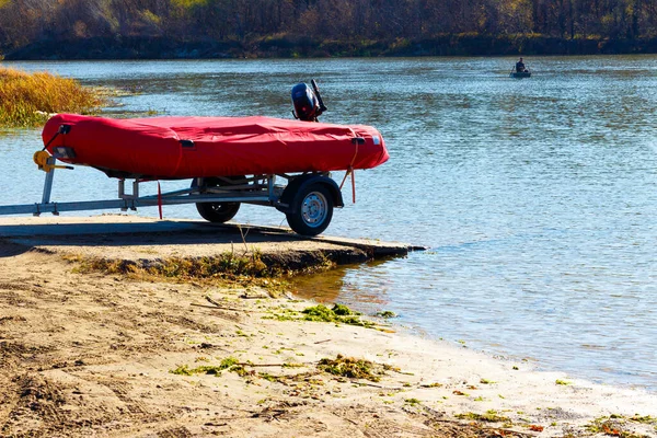 Um barco inflável em um reboque está antes de lançar na água Imagem De Stock