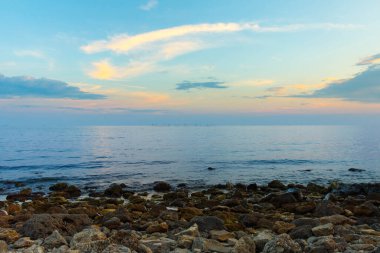 Güzel mavi gökyüzü ve taş kumsal Denizde gün batımından önce