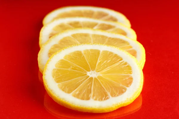 Rodajas de limón brillante maduro sobre un fondo rojo . —  Fotos de Stock