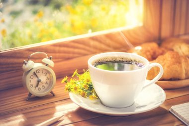 Kahvaltı için kahve ve çiçek. Sabah güneşiyle birlikte pencerenin kenarına yerleştirilmiş..