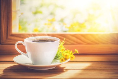 Kahve ve çiçek, sabah güneşiyle birlikte pencerenin kenarına konmuş..