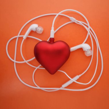 Purple heart madalyası turuncu bir arka plan üzerinde Sevgililer günü kavramdır. Kulaklıklar müzik, sevgi dolu bir kalp sembolü vardır.