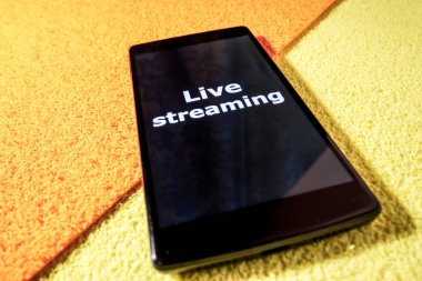 Canlı akış kavramı online röportaj. Akıllı telefon ve kulaklık renkli bir arka plan üzerinde. Fotoğraf videostreaming göstermek için kullanılabilir.