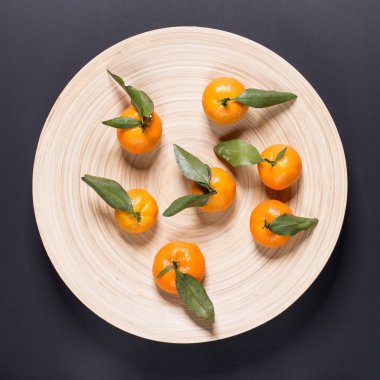 Bir tabak yapraklarla küçük mandalina ile. Meyve ile sulu ve sağlıklı beslenme kavramı.