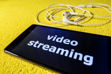 Video akış kavramı online röportaj. Akıllı telefon ve kulaklık renkli bir arka plan üzerinde. Fotoğraf videostreaming göstermek için kullanılabilir.