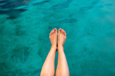 Balık peeling ve ayak bakım kavramı. Kadın bacaklar deniz suyu arka planı yalınayak.