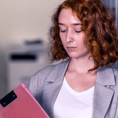 -Ofis koridorunda Kızıl saçlı bir kız kağıt için bir tablet tutar