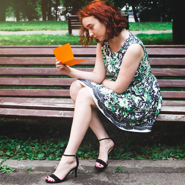 Una Chica Pelo Rojo Lee Una Postal Banco Del Parque —  Fotos de Stock