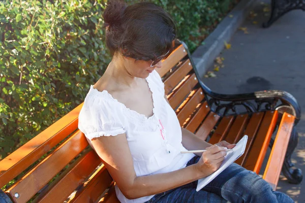 一位中年妇女坐在公园长椅上 那个黑发女孩城市公园的休息食谱 — 图库照片