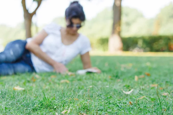 一个女孩在公园里看书 在绿色草地上的公园里平静的心情和放松的概念 穿着蓝色牛仔裤的中年妇女 — 图库照片