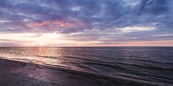 Baltık Denizi'ndeki deniz plaj gün batımında. Endişeli bulutlar ve dalgalar.