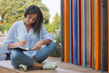 Esmer kız bir defter bir kalem ile yazar. Konsept tasarım düşünce ve yaratıcı fikirleri.