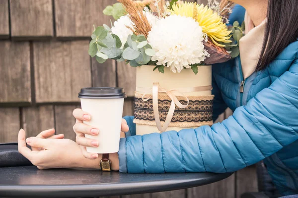 The girl sits in a cafe in the wicker chair in the fall and is waiting for a meeting.