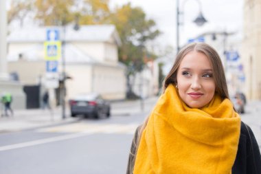 Genç kız turist şehrin tarihi merkezinde. Bir ceket ve sarı bir eşarp üzerinde bir sonbahar sokak uzun saçlı sarışın bir kadın.
