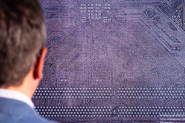 Concept of artificial intelligence and machine learning. A man looks at the PCB of the digital world.
