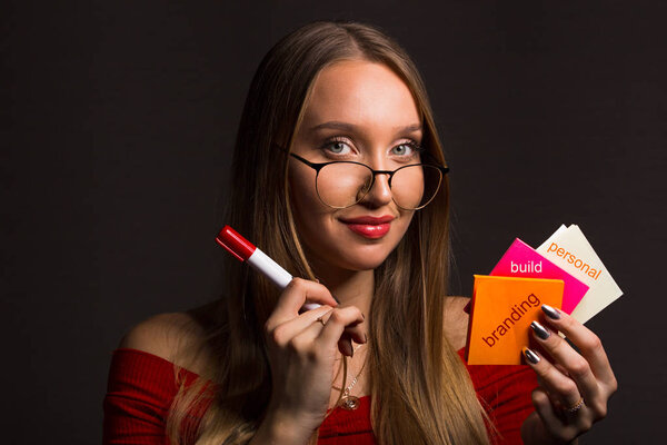 Концепция - создание персонального бренда. Блондинка с длинными волосами держит наклейки и маркер
.