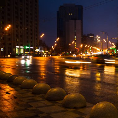 Gece şehir ışıkları yağmur altında. Arabalar hareket ve bulanık. Dış aydınlatma.