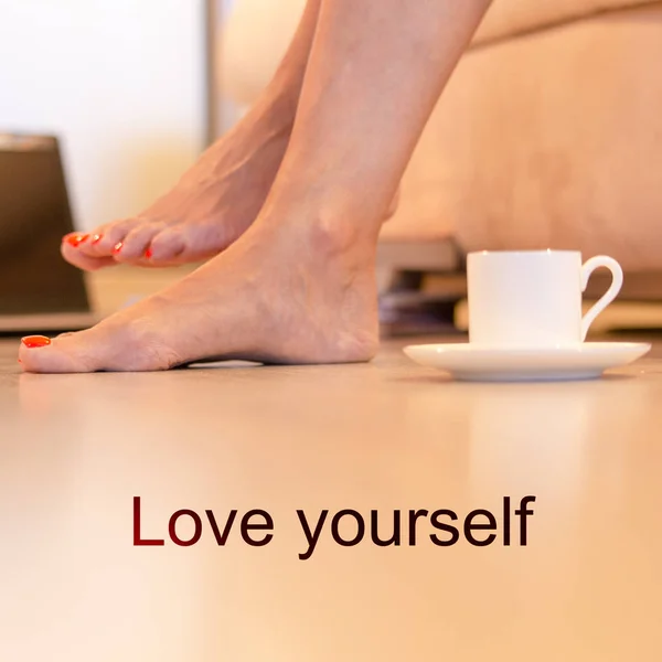 Concept - love yourself. Female barefoot legs with a pedicure and a cup of coffee. Concept - put everything off and take care of yourself.