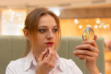 Kız Ofis Yöneticisi içinde bir iş bluz dudaklarını boyar ve ofiste bir kahve molası sırasında makyaj yapar.