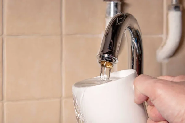 A jet of fresh drinking water from the tap in the kitchen and a glass. Photo to illustrate publications on water pollution or water scarcity on the planet.