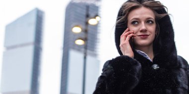 İş kadını siyah paltolu bir cep telefonu açık havada kışın arar. O bir iş soruna bir çözüm bulundu.