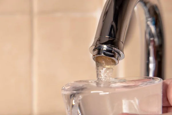 厨房水龙头里的新鲜饮用水和一杯玻璃 图片说明有关地球上水污染或缺水问题的出版物 免版税图库照片