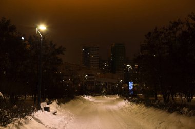 Kış şehir parkı akşamları düşük ışıkta. Yolları karla kaplı. Soğuk ve karlı hava yürüyüş.