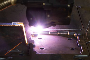 Endüstriyel bir fabrikada metali plazma makinesiyle keserken kıvılcım saçar. 