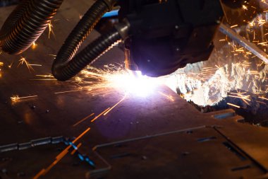 Endüstriyel bir fabrikada metali plazma makinesiyle keserken kıvılcımlar çıkıyor. Metalürji endüstrisinde parça üretimi.