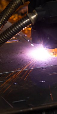 Endüstriyel bir fabrikada metali plazma makinesiyle keserken kıvılcım saçar. 