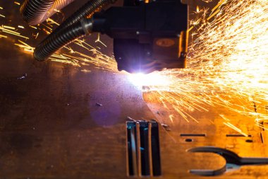 Endüstriyel bir fabrikada metali plazma makinesiyle keserken kıvılcım saçar. 