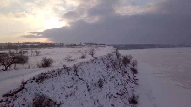 Vídeo aéreo 4k. Paisaje invernal en el pueblo y el río. Luz cálida del atardecer . — Vídeo de stock