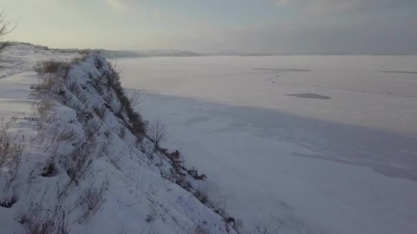 Vídeo aéreo 4k. Paisaje invernal en el pueblo y el río. Luz cálida del atardecer . — Vídeo de stock