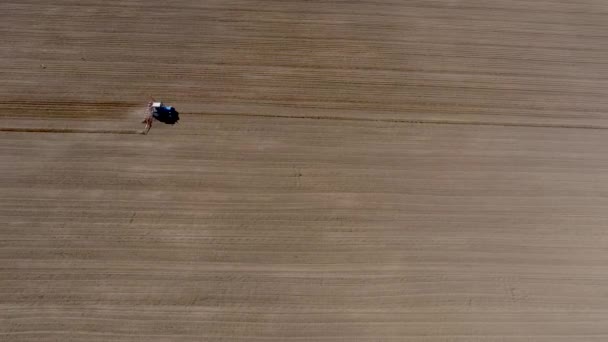 Vista aérea del tractor en el campo agrícola arado. Drone video — Vídeo de stock