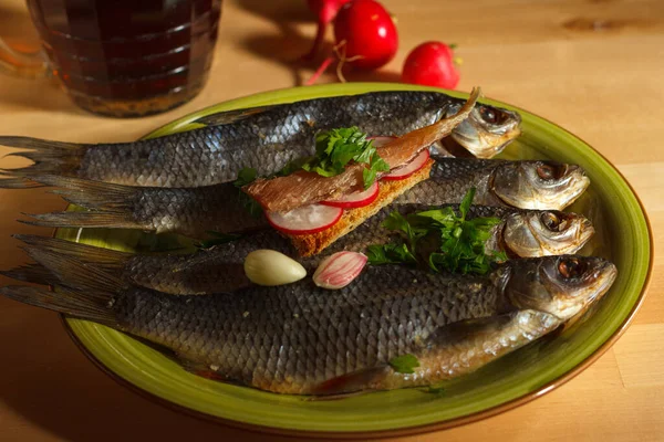 Dried roach on a green platter and a small sandwich with salted fish fillet, radish and parsley, a mug of dark beer in the background — Stock Image Dried Roach Green Platter Small Sandwich Salted Fish Fillet Radish Stock Picture