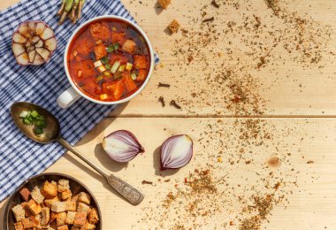 Bir bardak kırmızı kemik suyu ahşap bir masanın üzerinde eski bir kaşık ve kraker.