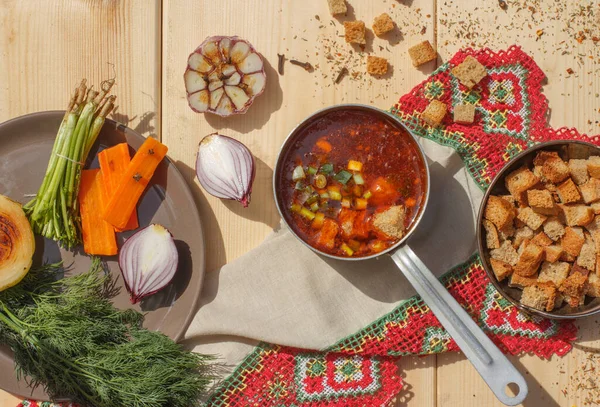 Porce husté polévky s sušenkami a bylinkami v naběračce a zeleninou na vaření. Rozložení na dřevěném pozadí — Stock fotografie