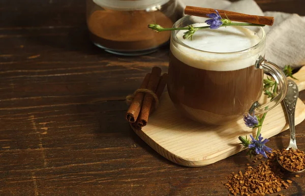 Cappuccino aus Zichorienwurzel, dekoriert mit Zimt und Blüte, auf dunklem Holzgrund, waagerecht mit Platz — Stockfoto