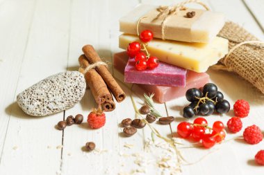 Doğal malzemeli renkli sabun parçaları, yakın plan. Taze böğürtlenlerle süslenmiş. Spa öğeleriyle bir ışık masasında