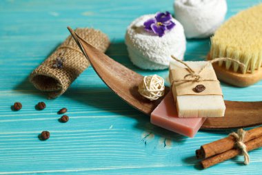 Bitkisel özlü doğal renk sabunu ve nazik spa bakımı için kuru masaj fırçası. Mavi ahşap bir arka planda, yakın plan.