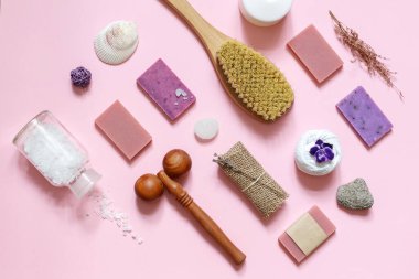 Pembe arka planda Spa vücut bakımı için doğal sabun ve aksesuarların çapraz düzeni