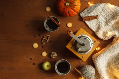 Turuncu balkabaklı sonbahar bezi, eski kahve öğütücüsü, kahve fincanı, ev yapımı örgü battaniye ve parlak çelenk. Boşluk ile üstte