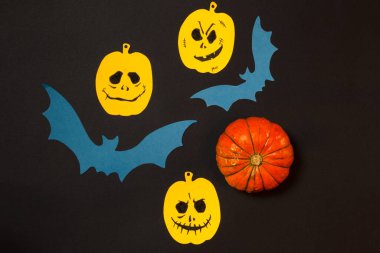 Cadılar Bayramı için arka plan. Sarı balkabakları ve boyalı yüzleri olan siyah kağıt üzerinde düz bir sayfa.. 